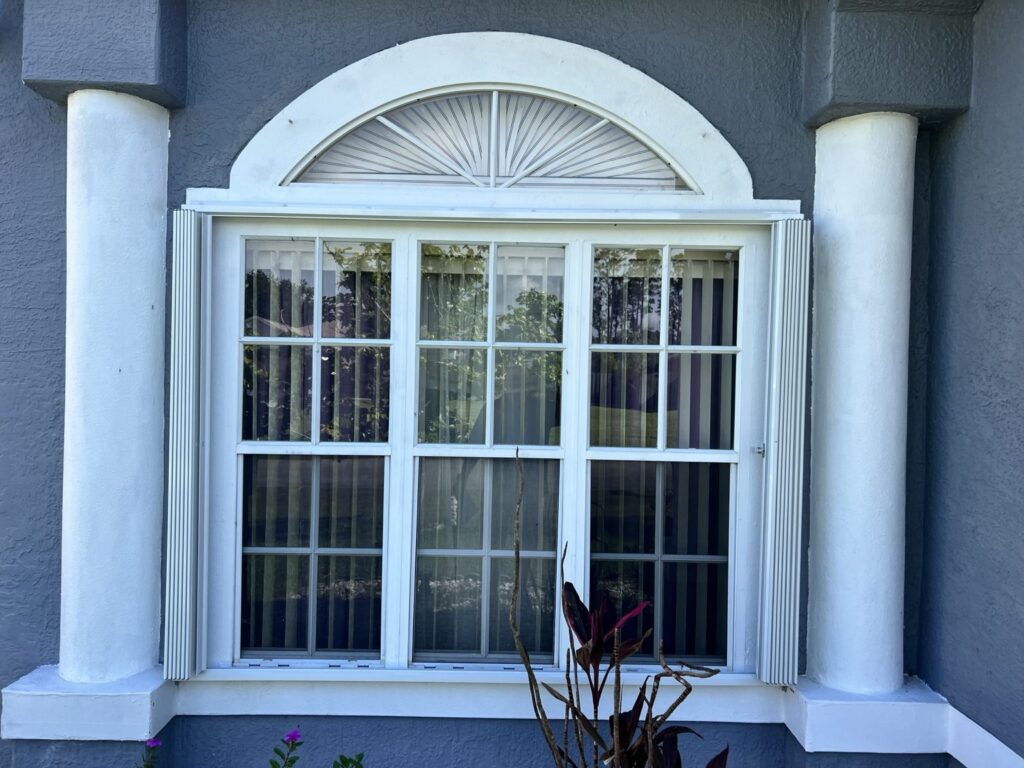 Accordion shutters stacked open beside an arched window