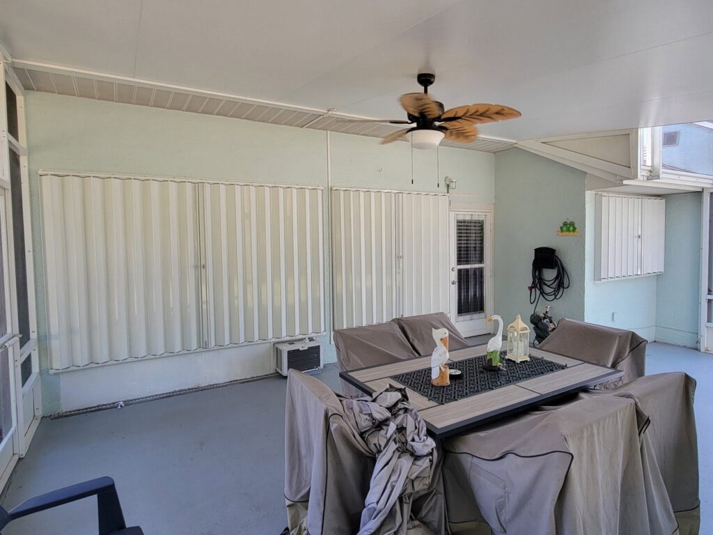 White accordion shutters installed across wide openings on a covered patio