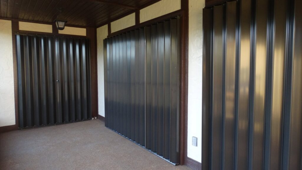 Dark-finish accordion shutters installed across several covered patio openings