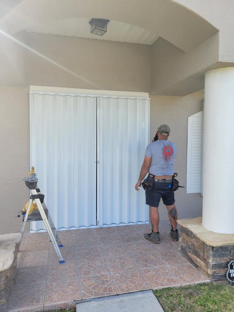 HSPM installer completing a white accordion shutter at a covered front entry