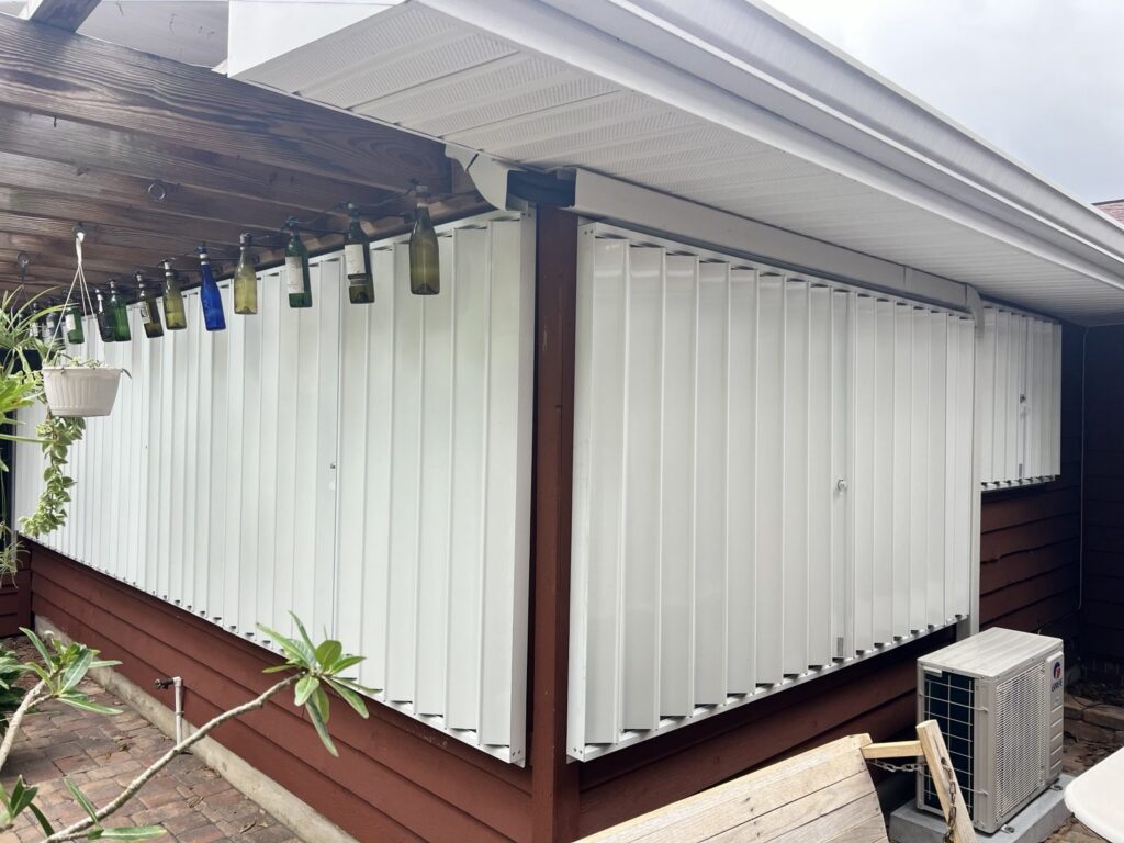 White accordion shutters installed around a covered porch