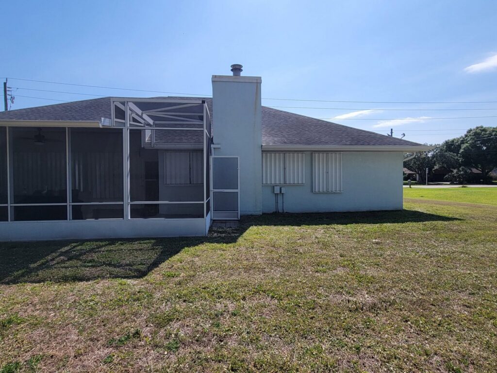 White accordion shutters installed across several rear openings of a Florida home