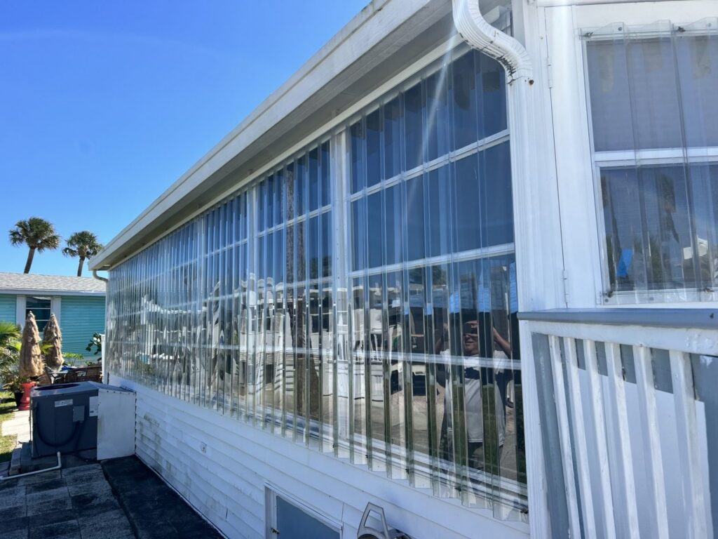 Clear Lexan storm panels installed across a long row of porch windows