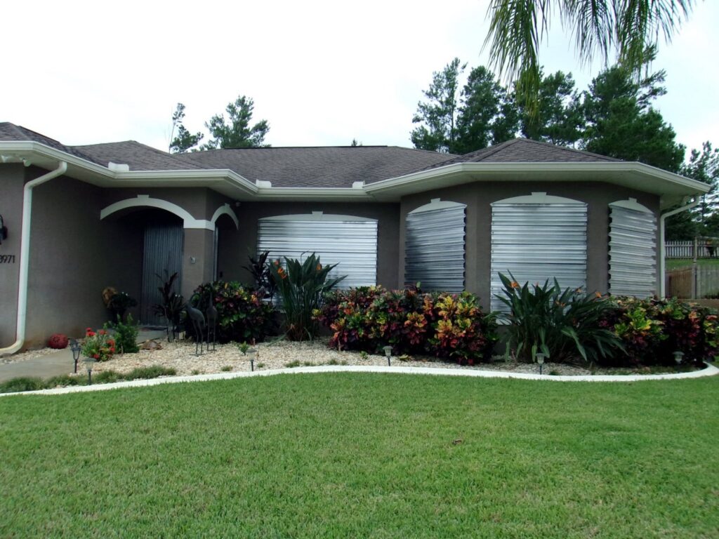 Removable metal storm panels installed over curved and rectangular openings on a Florida home